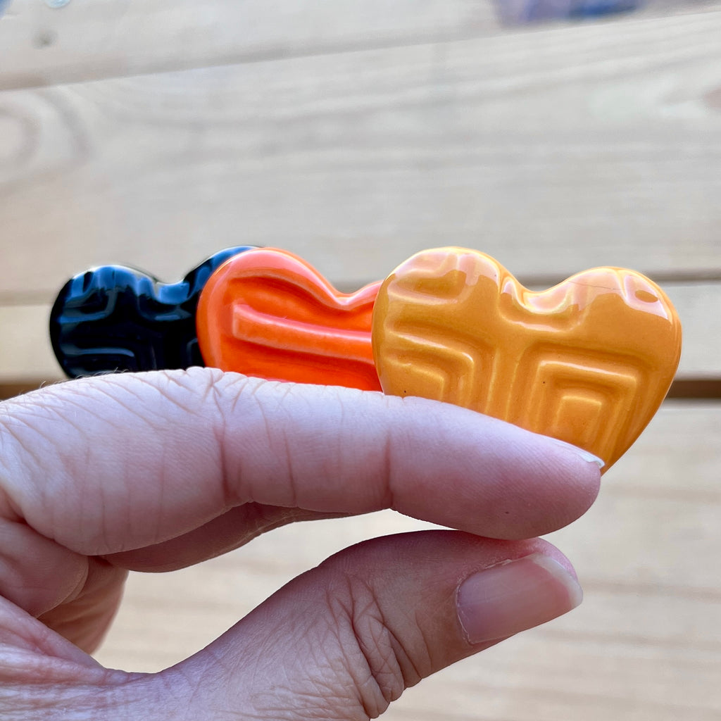 Three Halloween colored hearts in a hand