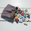 Colorful heart-shaped stones on a wooden surface with a drawstring bag.