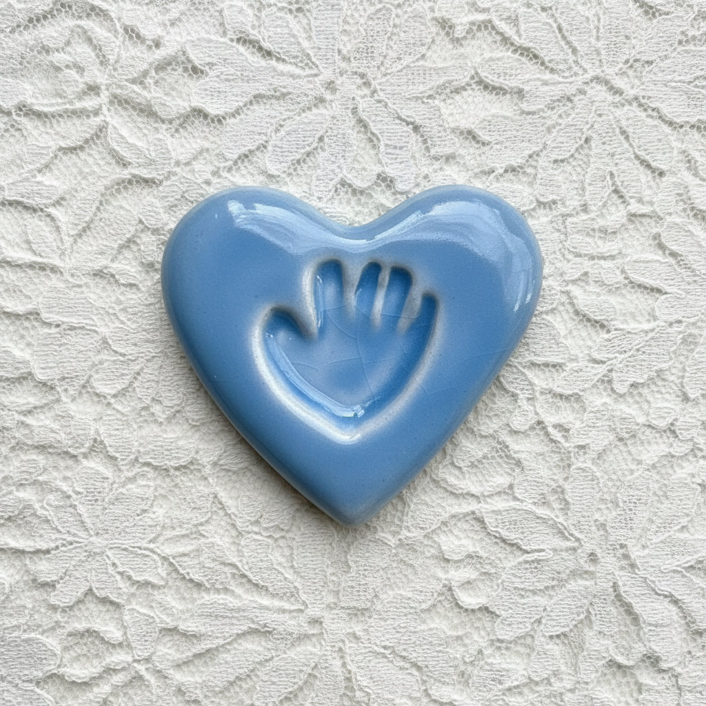 Blue ceramic heart with a handprint on a lace surface