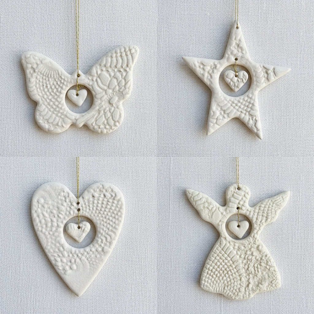 Four white ceramic ornaments shaped like a butterfly, star, heart, and angel on a fabric surface.