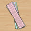Pink bookmark with text on an open book on a wooden surface