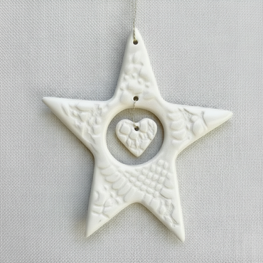 White textured star-shaped ornament with a heart in the center on a beige background