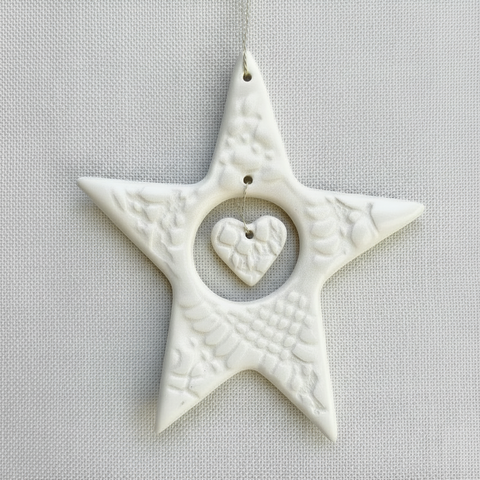 White textured star-shaped ornament with a heart in the center on a beige background