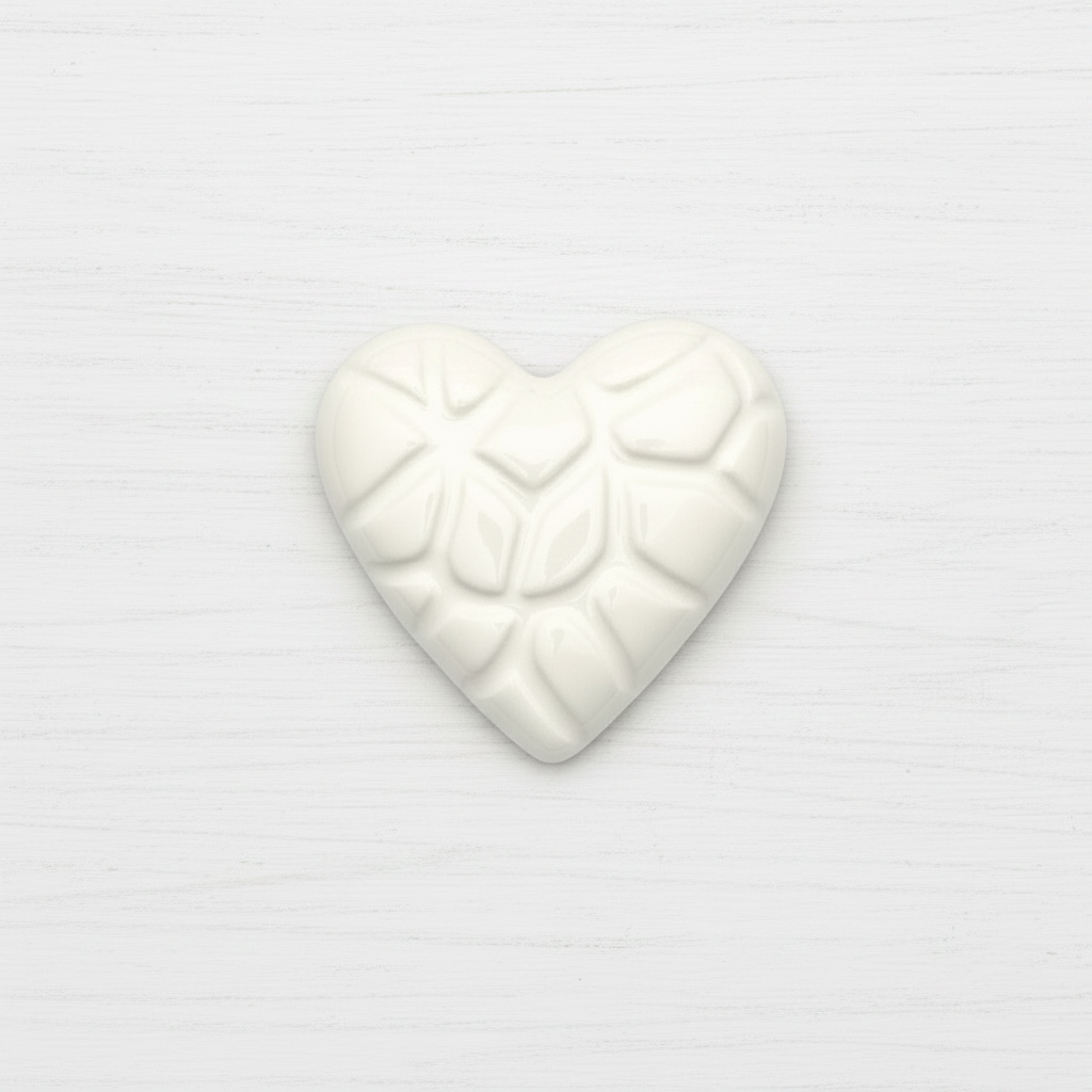 White heart-shaped ceramic with embossed design on a white background