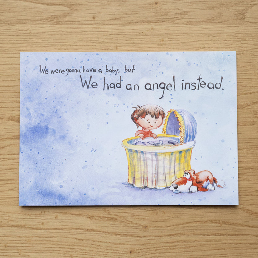 Book cover with illustration of a baby in a crib and text 'We were gonna have a baby, but We had an angel instead.' held on a textured surface.