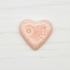 Heart-shaped pink soap with floral design on a white background