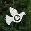 A white ceramic dove with a textured pattern and a heart-shaped cutout in the center, suspended by strings.