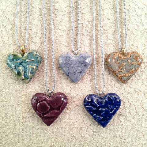 A collection of heart-shaped necklaces in various colors, each with a unique pattern.